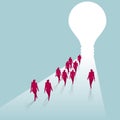 A group of businessmen walk towards the light bulb.